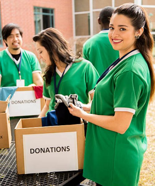 Organized group of multi-ethnic college student volunteers collect clothing donations for needy families in their community.